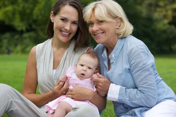 Happy mother and child sitting outdoors with grandmother — Stock Photo, Image