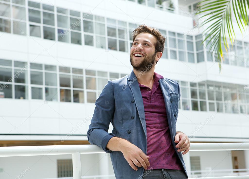 Smiling young man with beard standing in white building