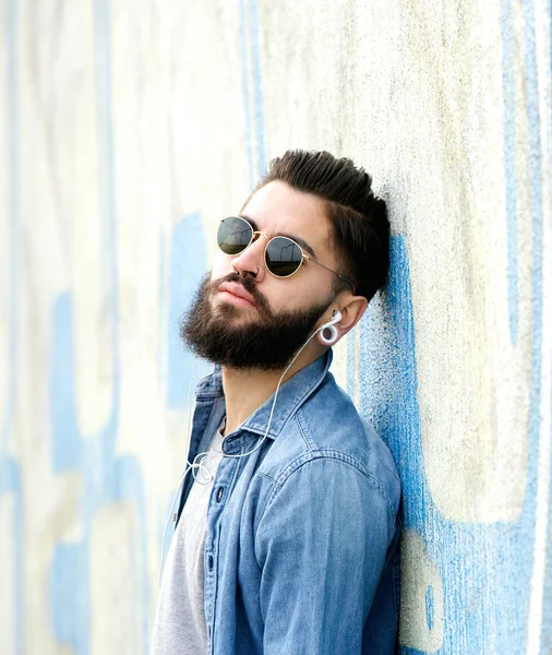 Koele kerel met de baard luisteren naar muziek met koptelefoon — Stockfoto