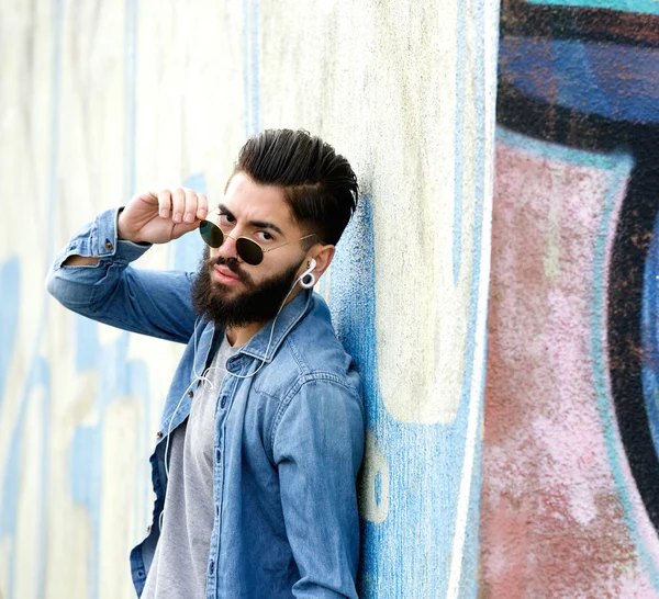 Chico guay con gafas de sol escuchando música con auriculares — Foto de Stock