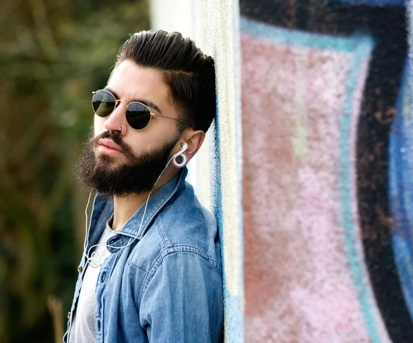 Jeune homme moderne avec barbe écoutant de la musique avec écouteurs — Photo