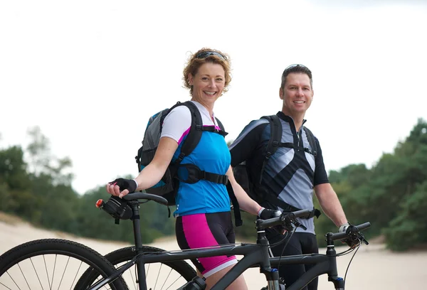 Hälsosamt leende par stående med sina cyklar utomhus — Stockfoto