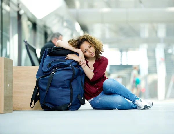 Уставшая молодая женщина отдыхает на сумке — стоковое фото
