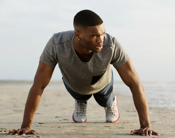 Sportovní mladý muž dělá push up na pláži — Stock fotografie