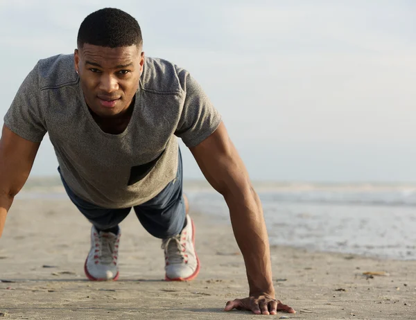 Young black man doing push ups at the beach Royalty Free Stock Images