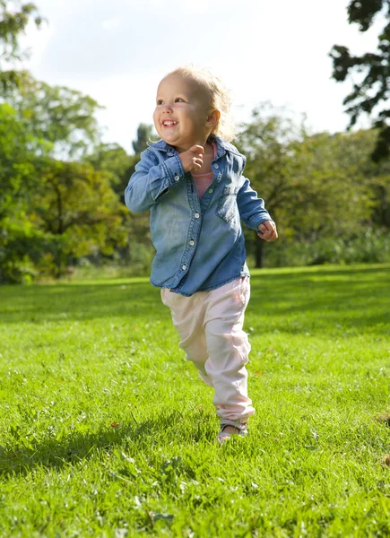 Little girl running and playing outdoors Stock Image