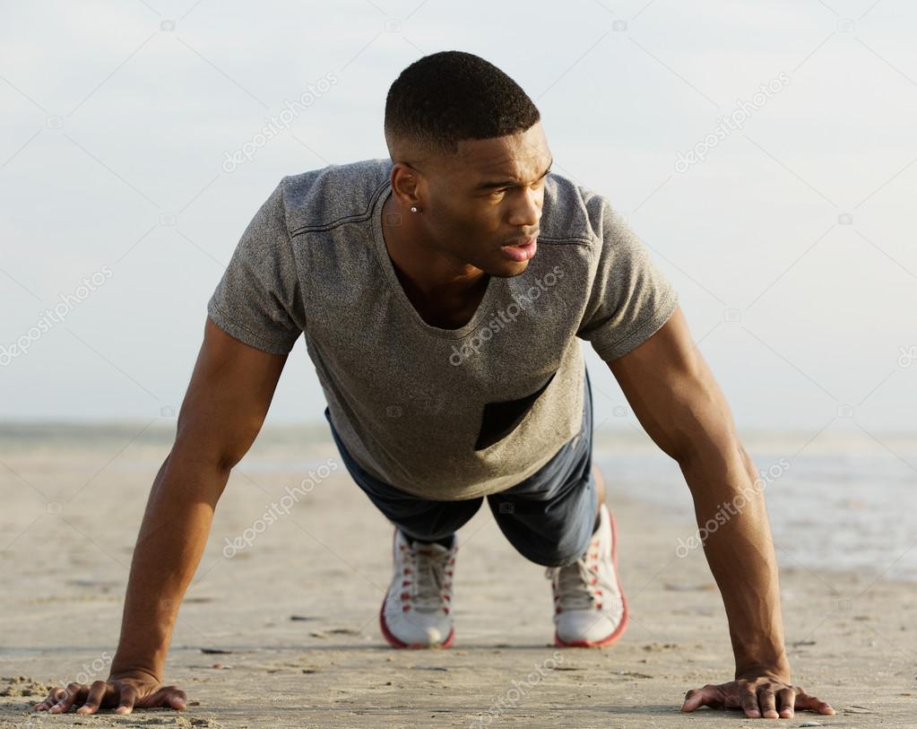 Athletic young man doing push ups at the beach