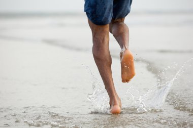 Man running barefoot in water clipart