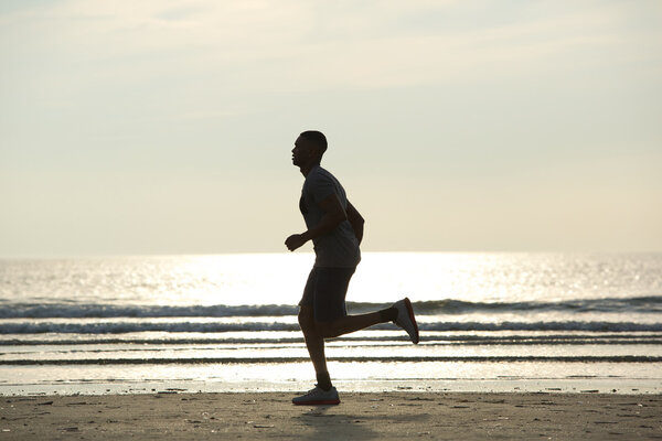 Здоровый молодой человек бегает по пляжу
 