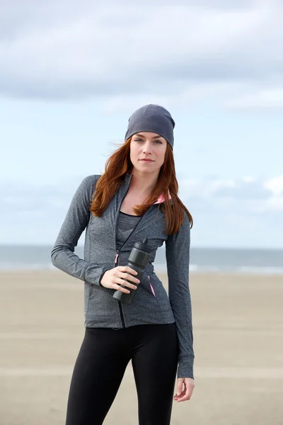 Sporty woman standing outdoors with water bottle — Stock Photo, Image