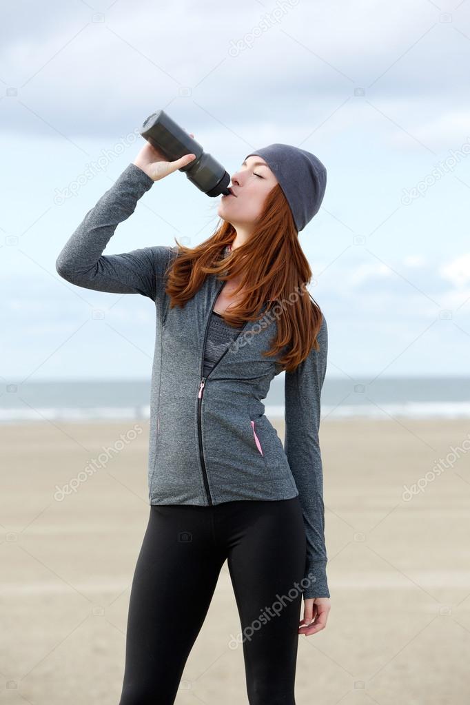 Young sports woman drinking water from bottle outdoors