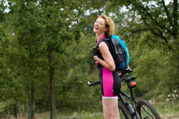 Mujer alegre sonriendo con bicicleta al aire libre —  Fotos de Stock