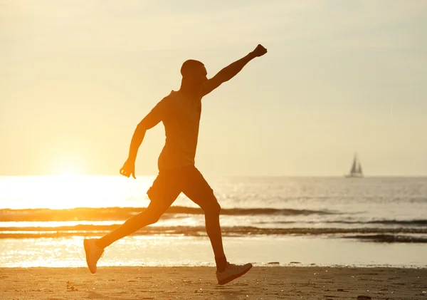Ein Mann läuft mit erhobener Hand am Strand — Stockfoto