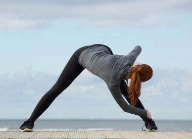 Dışarıda esneme egzersizleri yapan genç bir kadın.