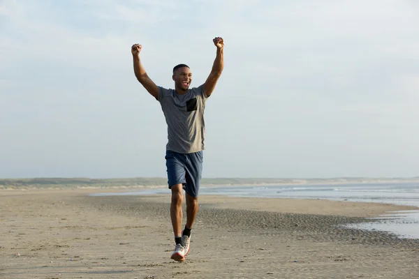 Man loopt op strand met uitgestrekte armen — Stockfoto