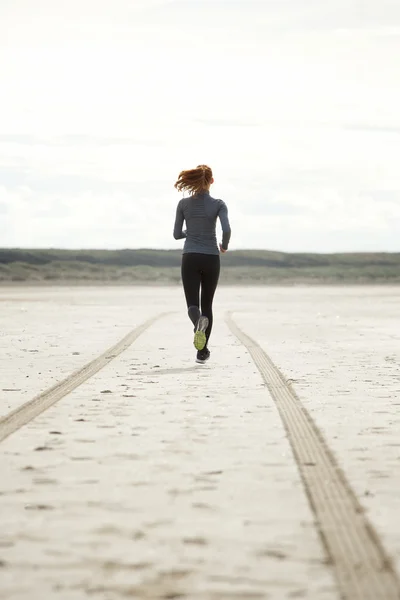 Молодая женщина бежит по пляжу — стоковое фото