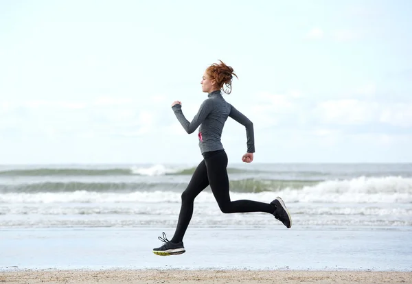 Gesunde junge Frau läuft am Strand — Stockfoto