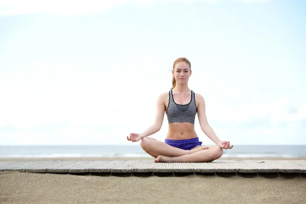 Hermosa joven sentada al aire libre en pose de yoga — Foto de Stock