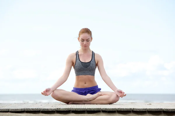 Mujer joven sentada al aire libre en posición de yoga — Foto de Stock