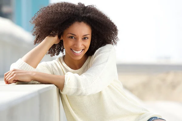 African american vrouw glimlachen met krullend haar zitten buiten — Stockfoto