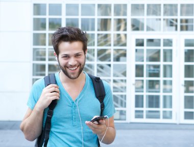 Genç adam cep telefonu ve sırt çantası ile gülümseyen