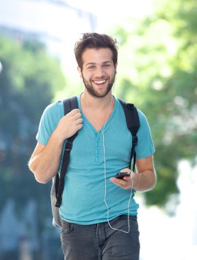 Mutlu genç adam açık havada cellphone ile yürüyor 