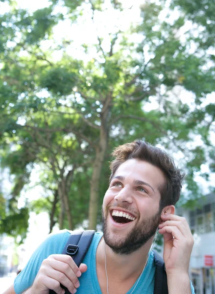 Happy young man outdoors with backpack and earphones — Stock Photo, Image