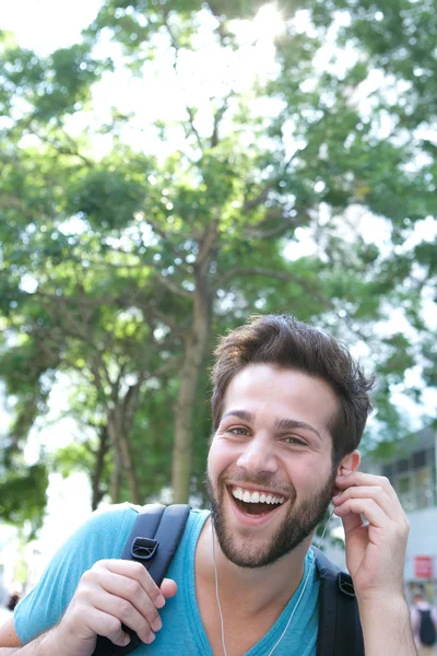 Ung man skrattar med hörlurar utomhus — Stockfoto