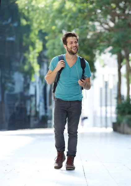 Joven alegre caminando con teléfono móvil y bolsa —  Fotos de Stock