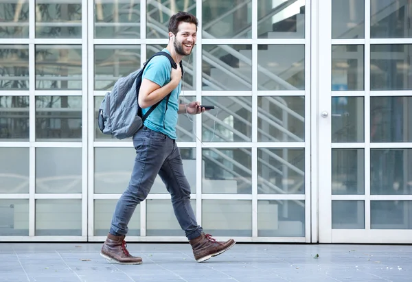 Young man walking on sidewalk with mobile phone and bag — Stock Photo, Image