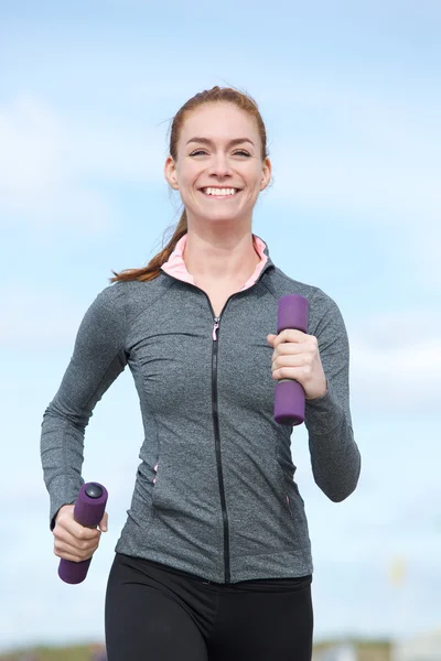 Jonge vrouw lopen met gewichten in handen — Stockfoto