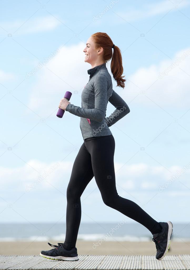 Happy young woman jogging with weights