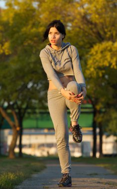 güzel bir genç kadın açık havada streç egzersizleri yapıyor