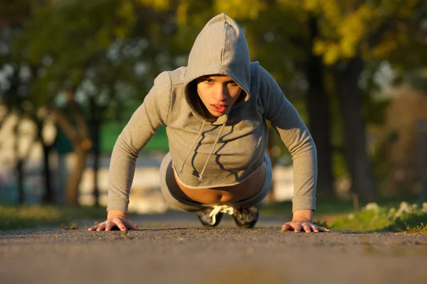 Fit young woman doing push ups outdoors — Stock Photo, Image