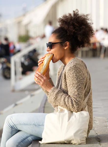 Junge Frau entspannt sich im Freien und isst Essen — Stockfoto