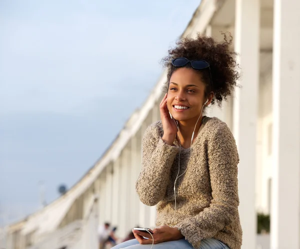 Jovem mulher sorrindo ao ar livre e ouvindo música — Fotografia de Stock