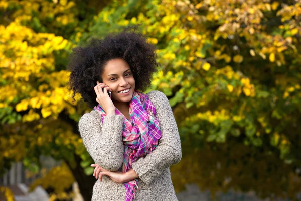 Усміхнена молода жінка телефонує на відкритому повітрі — стокове фото