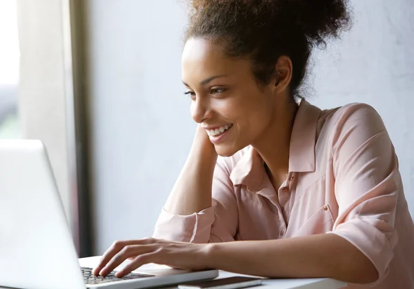 Schöne junge Frau lächelt und schaut auf Laptop-Bildschirm — Stockfoto