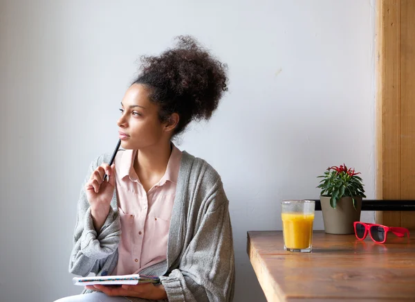 Young woman sitting at home with pen and paper — Stock Photo, Image