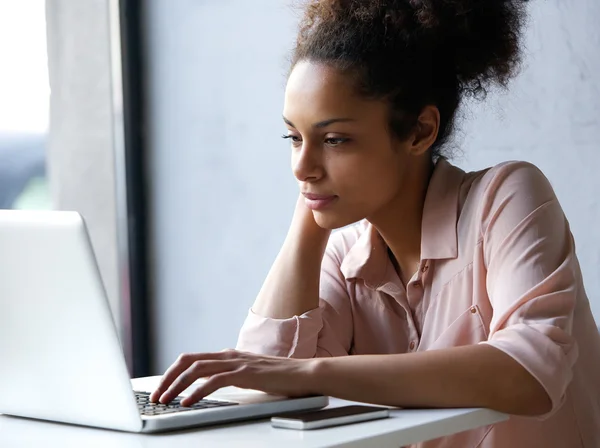 Ung svart kvinna tittar på laptop Royaltyfria Stockfoton