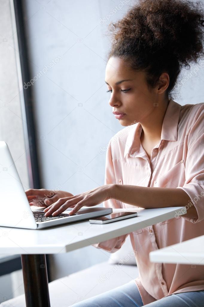 Young african american woman typing on laptop