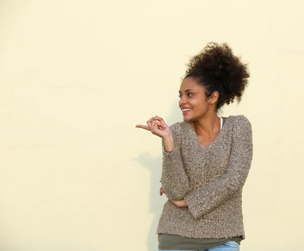 Jovem mulher sorrindo e apontando dedo — Fotografia de Stock