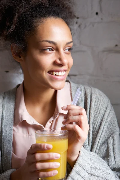 Νεαρή γυναίκα χαμογελώντας με ποτήρι χυμό πορτοκαλιού — Φωτογραφία Αρχείου