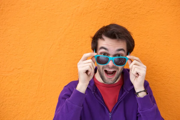 Young man laughing and holding sunglasses — Stock Photo, Image