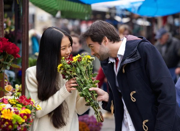 Happy couple smelling flowers together — Stock Photo, Image