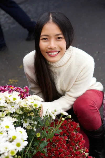 Schöne junge asiatische Frau lächelt mit Blumen im Geschäft — Stockfoto