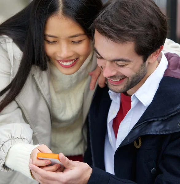 Пара улыбается и смотрит на сообщение на мобильном телефоне вместе — стоковое фото