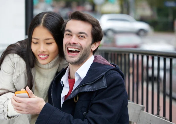 Happy νεαρό ζευγάρι χαμογελώντας με το κινητό στην πόλη — Φωτογραφία Αρχείου