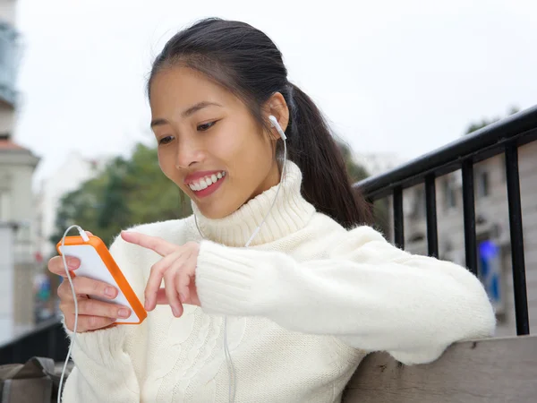 Jonge Aziatische vrouw die lacht met mobiel en oortelefoons — Stockfoto