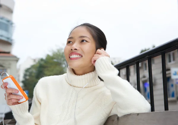 Glimlachend jonge vrouw luisteren naar muziek op mobiele telefoon — Stockfoto